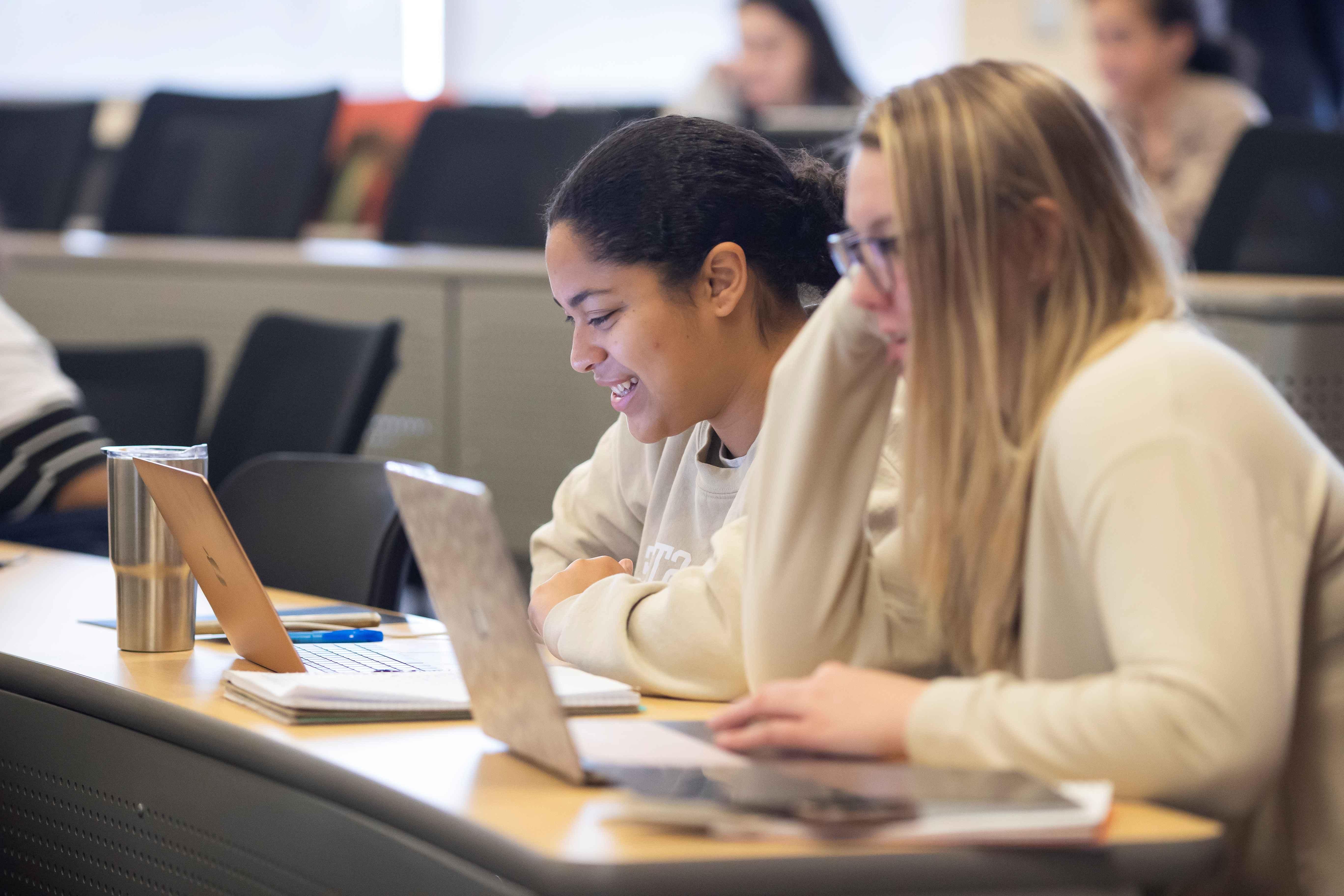 Girl taking notes on laptop in class.