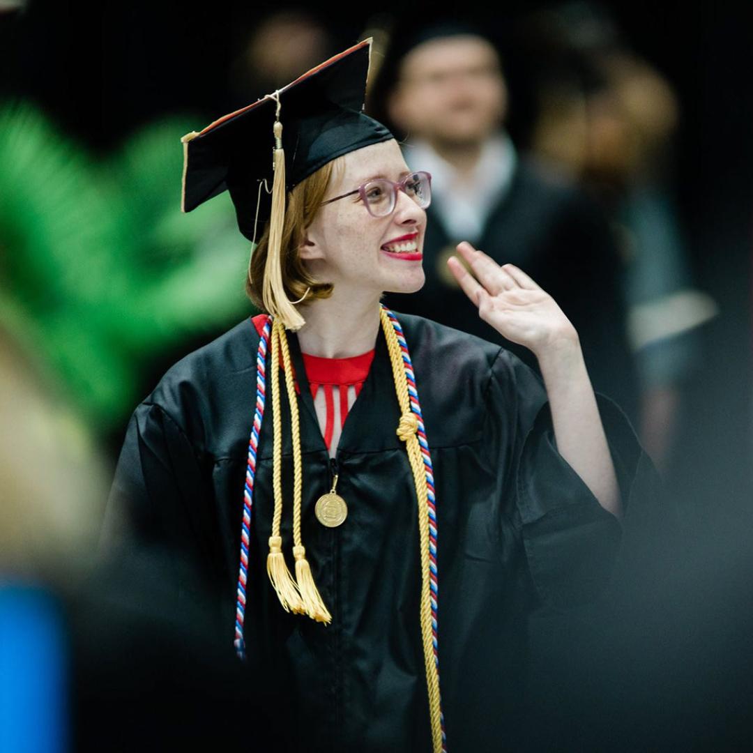 Photo of 赛迪 walking at graduation; she's waving at the crowd